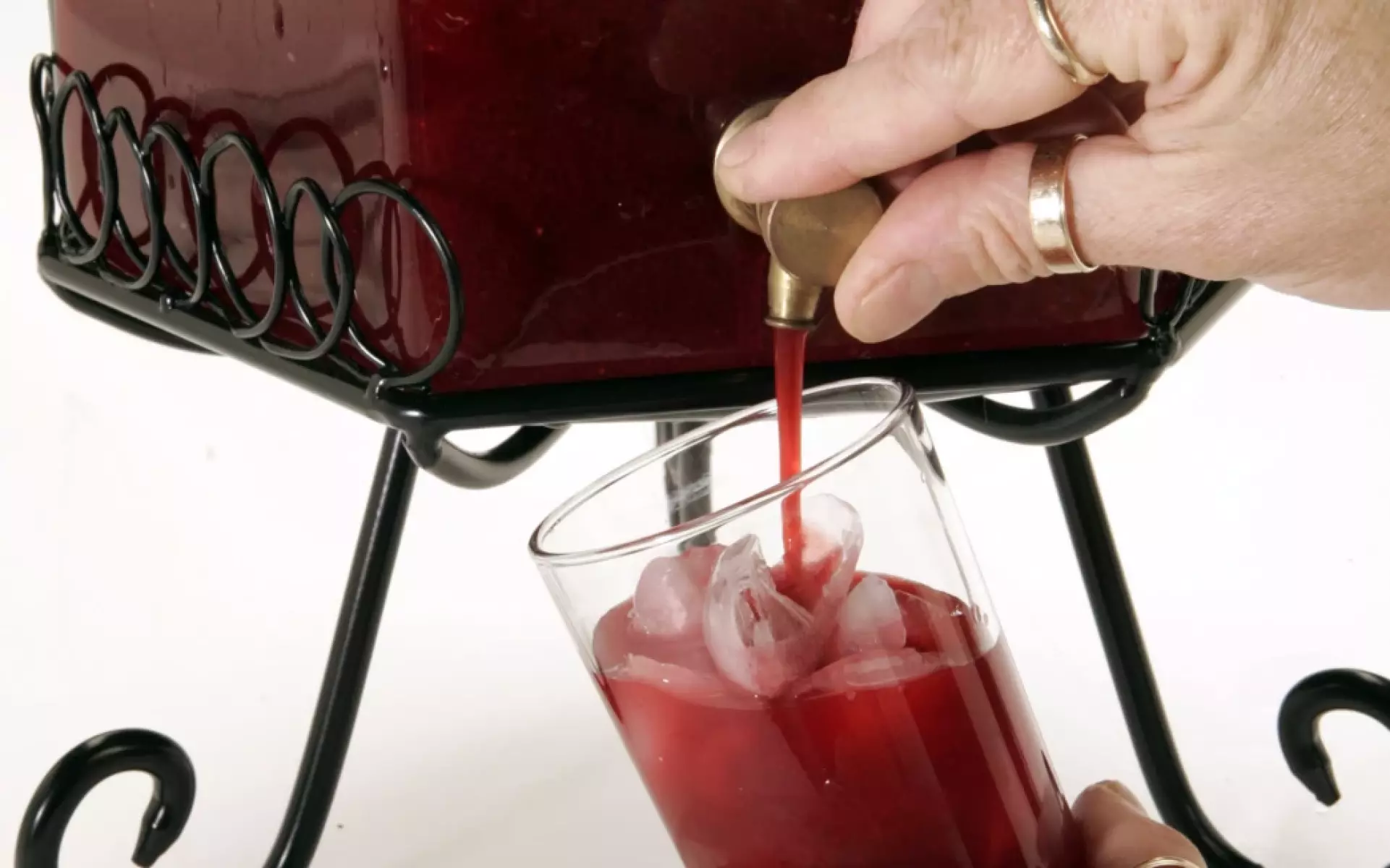 Close-up of someone pouring a red drink into a glass